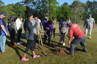 Students and staff planting a tree on campus.