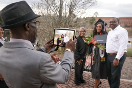 A graduate poses for a photo with her family outside of the recreation and wellness center.