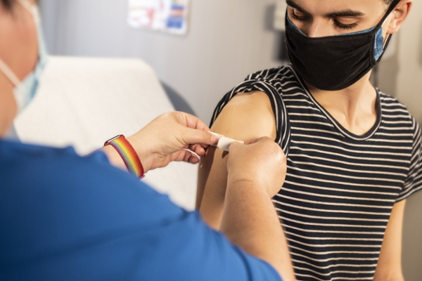 Nurse placing a bandage on a patient's arm after receiving a vaccine. 