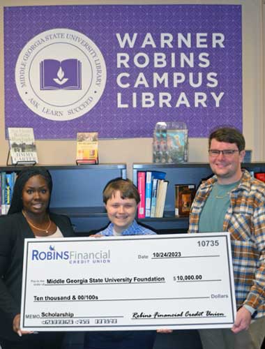 Chelsea Crawford with Robins Financial Credit Union presents check to Landon Derr and Justin Fussell.