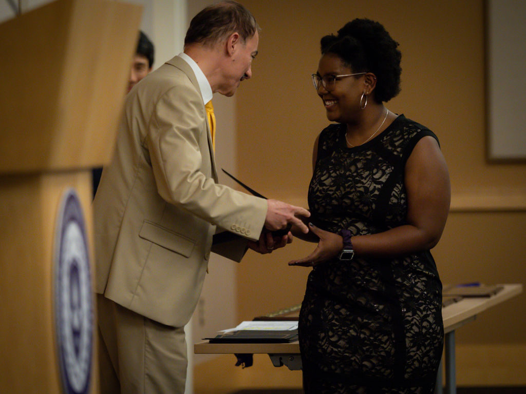 Student shaking hands with a faculty member after accepting her award at 2023 Honors Convocation.