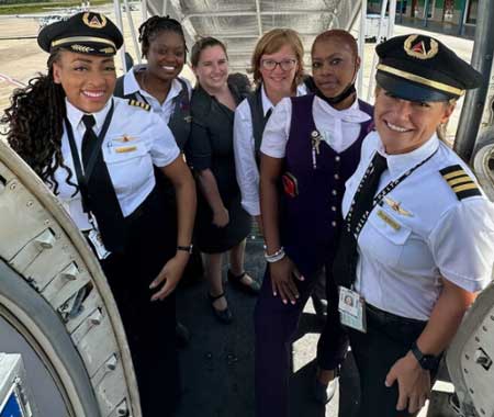 Anya Kearns and her all-female crew pose for a photo next to the Delta plane in Belize. 