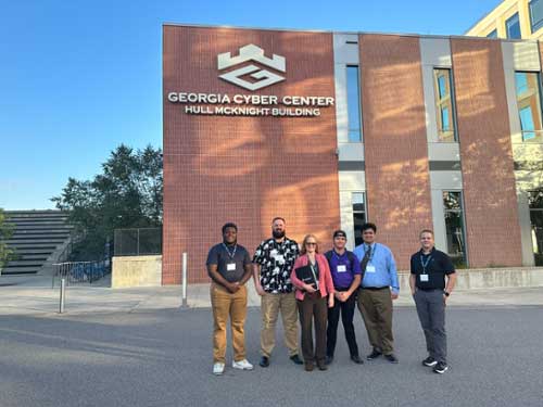 MGA’s Collegiate Penetration Testing Competition team was made up of students (l-r in image) Coby Roye, Ben Behnke, Stephanie James (captain), Damian Allen, and Dylan Eddie, with coach Dr. Alan Stines (far right).