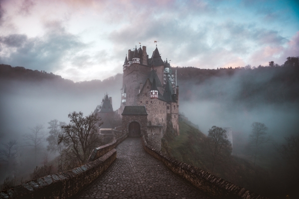 Close up photo of a castle surrounded by mist at sunrise. 