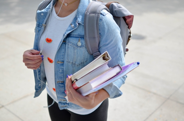 Student holding books and wearing a bookbag. 