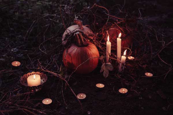 Pumpkin sitting between lit candles in a foggy field. 