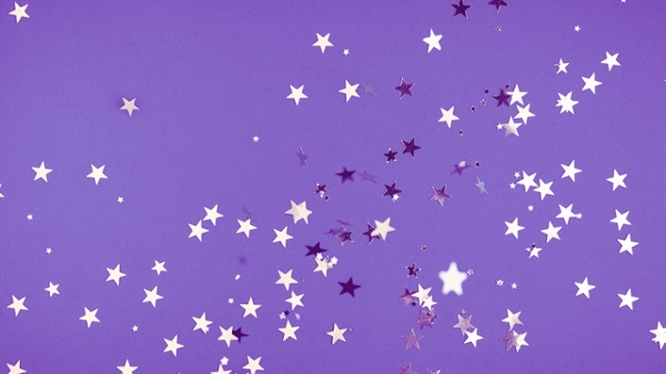 Silver star confetti sitting on a purple backdrop.