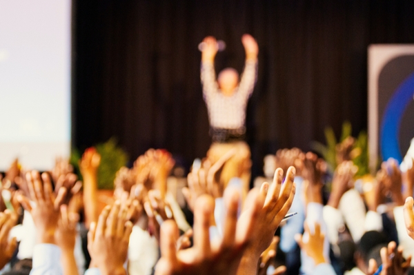 People with their hands raised during a conference. 
