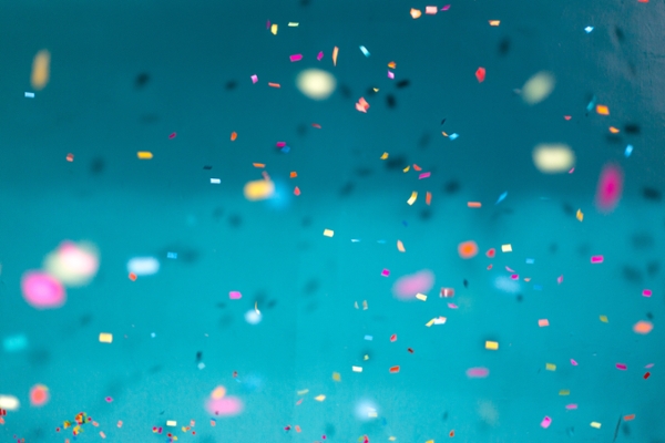 Confetti falling over a blue backdrop. 