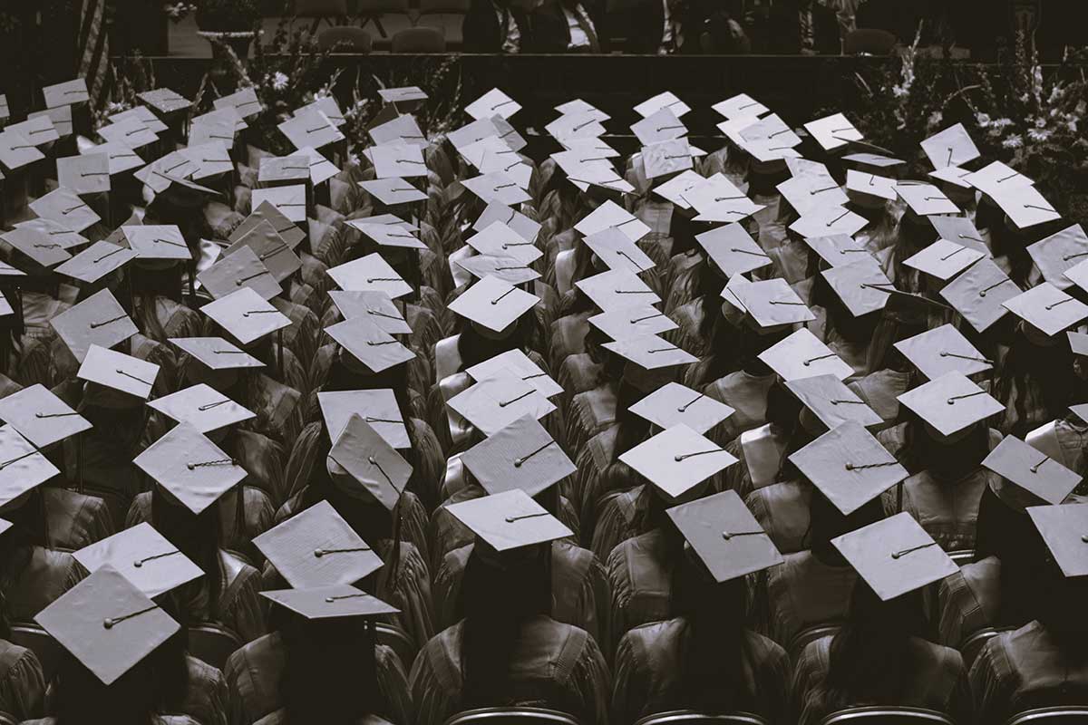 Graduates sit in a crowd at graduation.