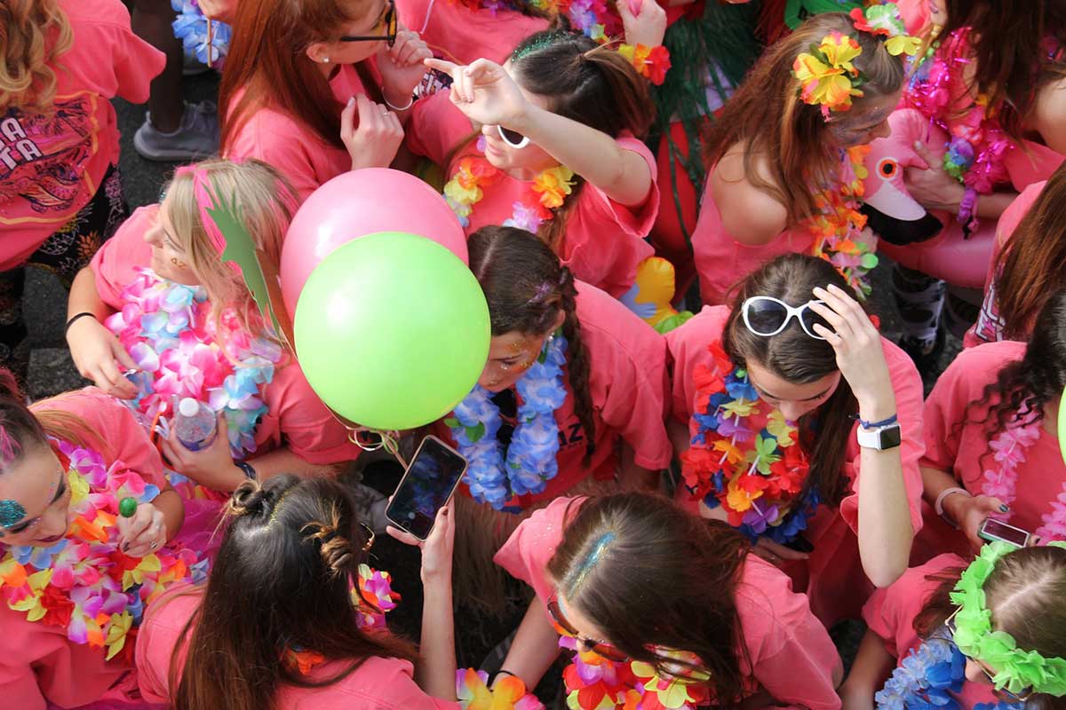 Women wearing pink celebrate at a festival. 