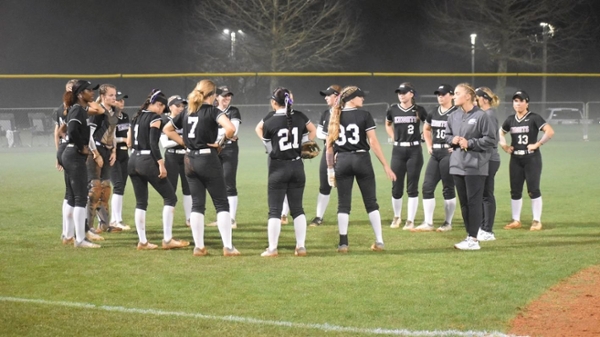 MGA softball team huddles on the field during a game. 