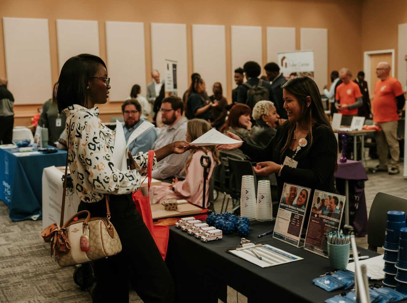 Female student exchanges papers with a job representative at a career fair.