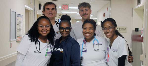 Troya Thomas (in blue scrubs), an RN at Piedmont Macon, is the clinical instructor for MGA nursing students rotating through clinical settings at the hospital. Piedmont funds her position through a special partnership with the University. She is shown with some of the MGA nursing students she has instructed.