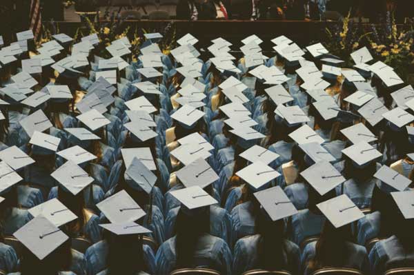 Graduates sit in a crowd at a commencement ceremony. 