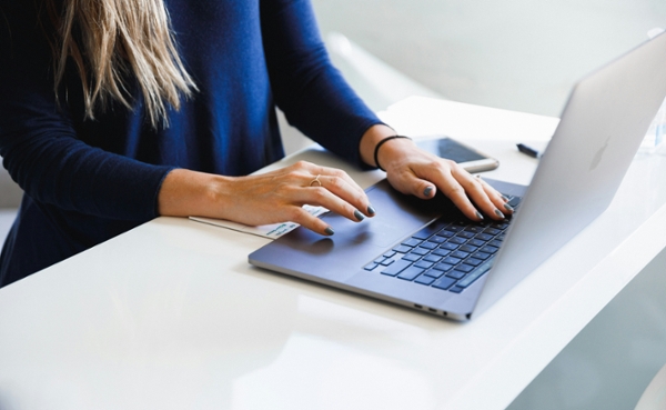 Woman types on a laptop at a desk.