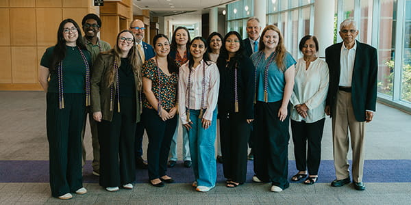A group photo of MGA study abroad attendees and faculty standing in a sunlit campus building.