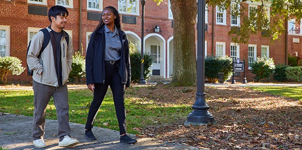 Two MGA students walking through campus together talking and smiling.