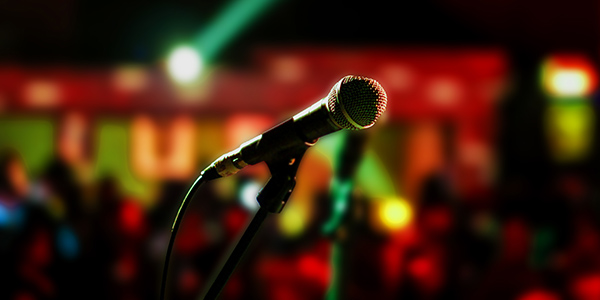Image of a microphone on a stand in a crowded room.