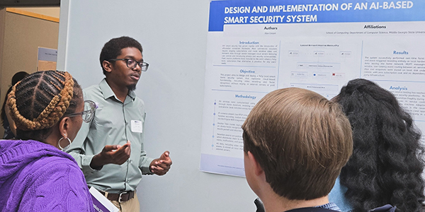 A student presenter at Middle Georgia State University's STEMposium discusses a research poster titled "Design and Implementation of an AI-Based Smart Security System" with a group of attendees.