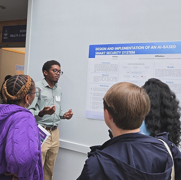 A student presenter at Middle Georgia State University's STEMposium discusses a research poster titled "Design and Implementation of an AI-Based Smart Security System" with a group of attendees.