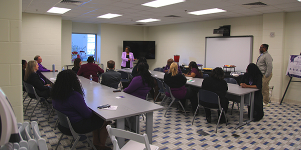Wide shot of ceremony, with attendees listening to speaker at the front of the room.