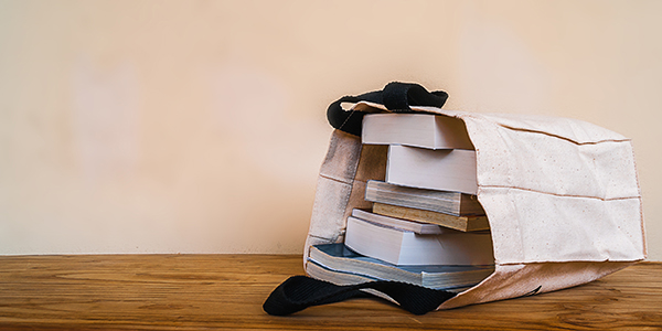 A bag full of books lying on its side on a table.