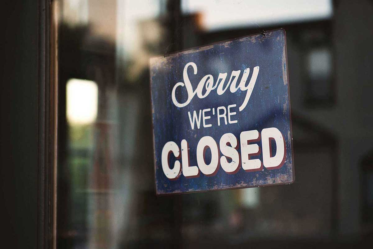 "Sorry we're closed" sign hanging in a store window.