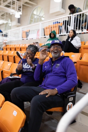 Knights men's basketball player's family sitting in the stands during a game in MGA gear. 