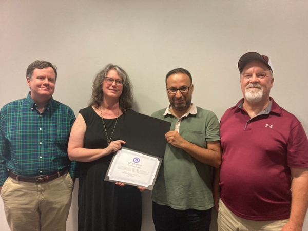 Solmaz, third from left, is shown receiving a certificate of appreciation from MGA English faculty members Dr. John Murphy, Dr. Benita Muth, and Dr. Chris Cairney. 