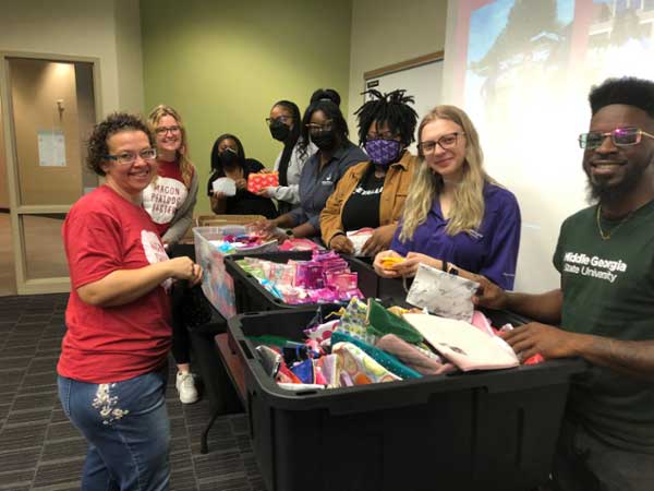 MGA volunteers with Macon Periods Easier packing cosmetic bags with menstrual products.