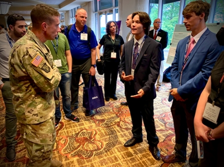 U.S. Army Cyber Command Brig. Gen. Paul T. Stanton, Deputy Commanding General (Operations) at Fort Gordon, Augusta (left), listens to the School of Computing’s Department of IT CyberKnight Ambassadors Damian Allen (left) James Orr (right) and discuss their research at the 2022 TechNet Augusta Research Student Poster Show Wednesday, August 17, 2022, at the Augusta Marriott Hotel and Convention Center.