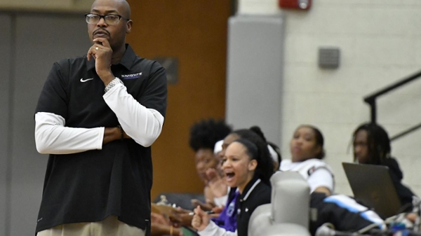 Women's basketball coach Ligon standing while watching a game on the sidelines.