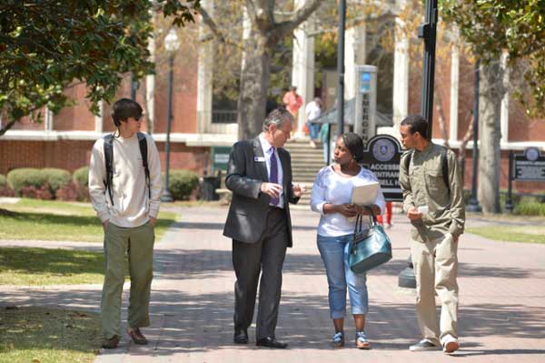 President Blake walking and talking with students on campus.
