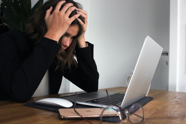 Stressed woman holding her head in her hands at her desk at work.