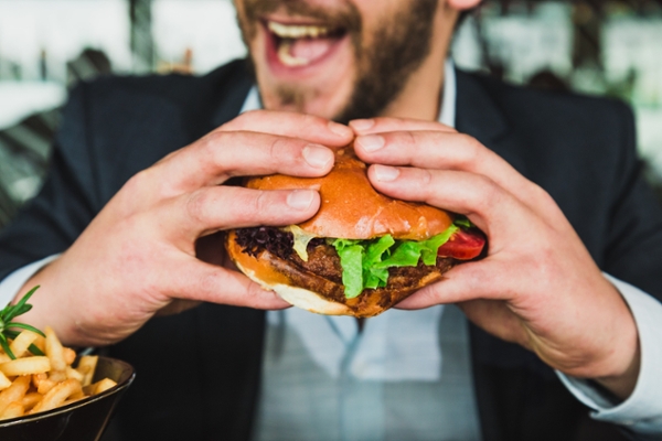 Man in a suit smiling while holding a burger.