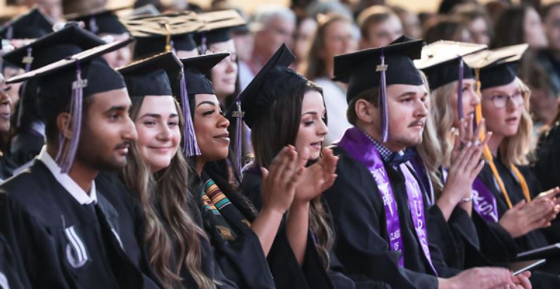 Graduates sitting in the crowd at a commencement ceremony. 