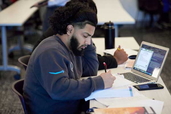 MGA student studying at a desk wearing an Amazon sweatshirt. 