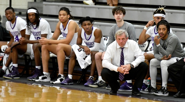 Knights men's basketball sitting on the sidelines with their coach.