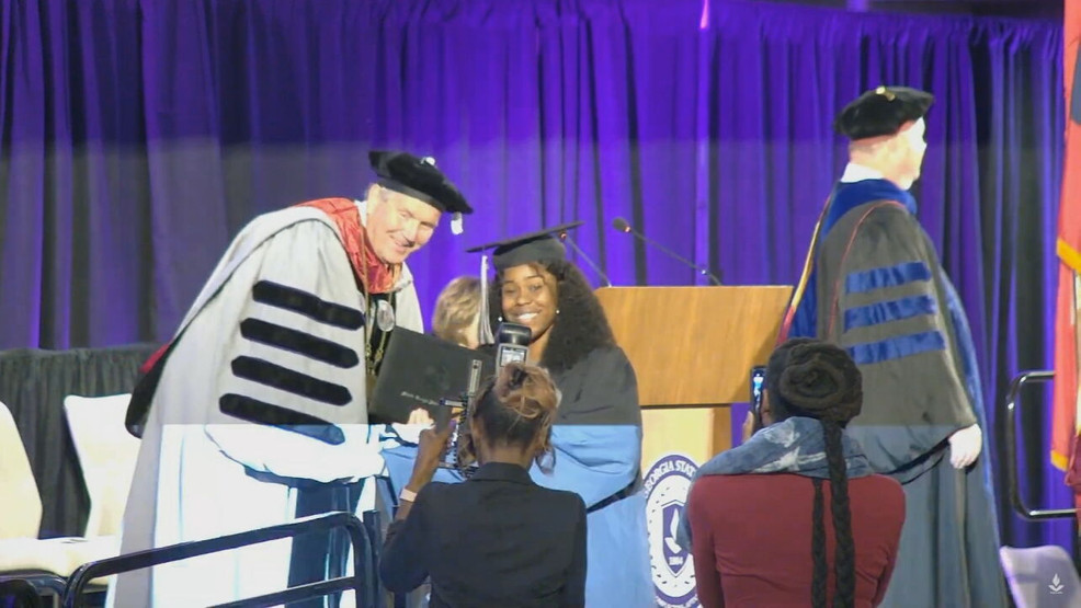 President Blake presenting a graduate with their degree. 