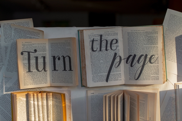 Books laying open with the phrase "turn the page" written on them in black marker. 