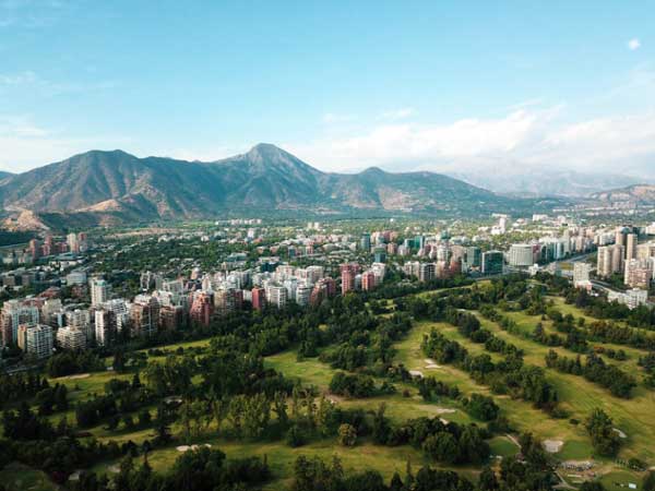 A golf course surrounded by a city beneath mountains in Santiago, Chile.