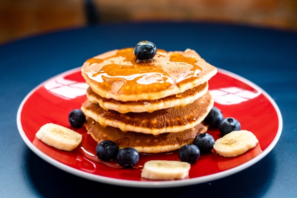 Stack of pancakes and fruit on a plate. 