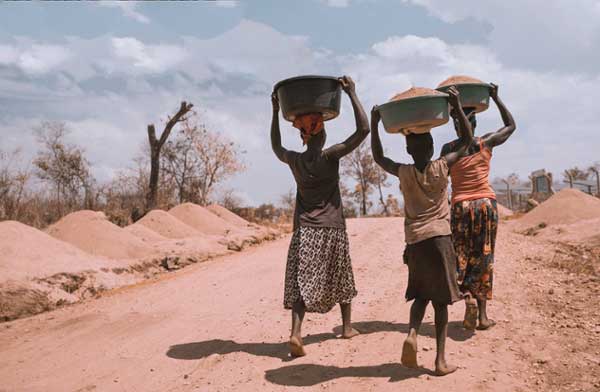 Three women carrying basins in  Rhino Refugee Camp, Arua, Uganda.