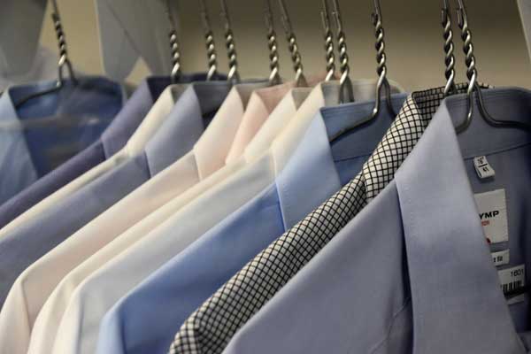 Assorted-colored business shirts and suit jackets hanging in a closet. 