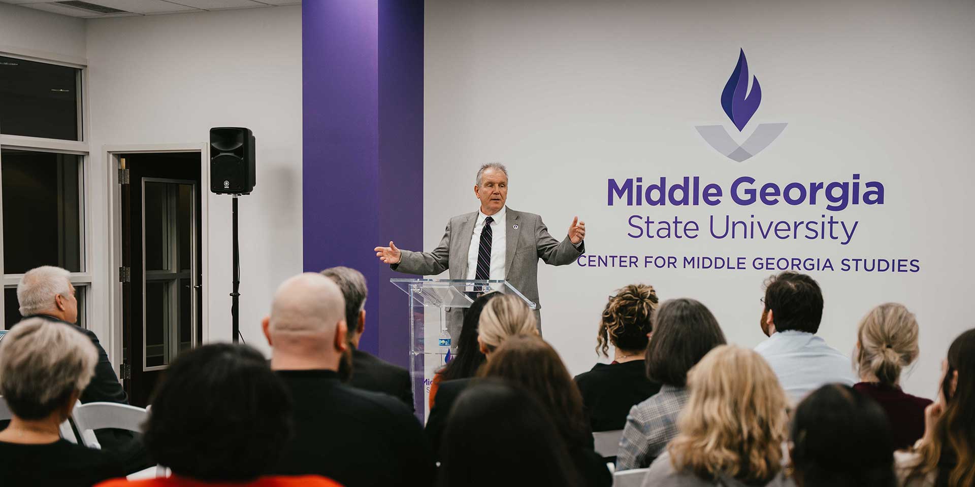 President Blake speaks at a podium in the Center for Middle Georgia Studies.