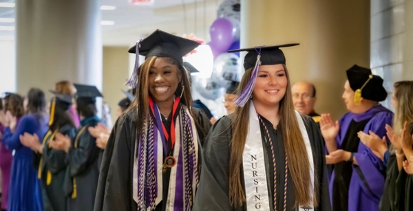 Two female graduates processing at MGA's spring 2024 commencement ceremony. 