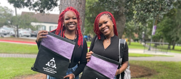 Female students hold Office of Campus Culture & Community gym bags.