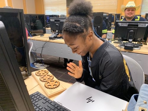 CyberKnight student looks at gears made of wood. 