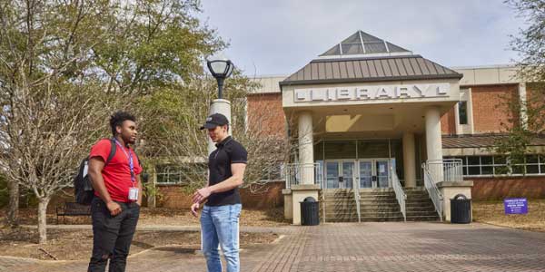 Two male MGA students talk outside of the Macon Campus library. 